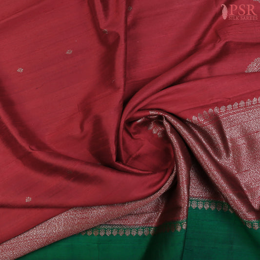 PSR Silks unveils a magnificent Berry Red Banaras Jute Silk Saree, beautifully paired with a luxurious Dark Green combination. 